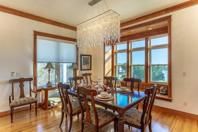 dining area featuring light wood-type flooring, an inviting chandelier, a healthy amount of sunlight, and crown molding