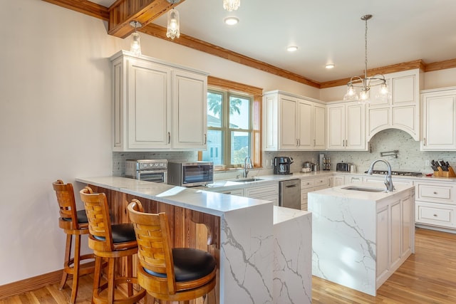 kitchen with kitchen peninsula, tasteful backsplash, sink, light hardwood / wood-style flooring, and hanging light fixtures