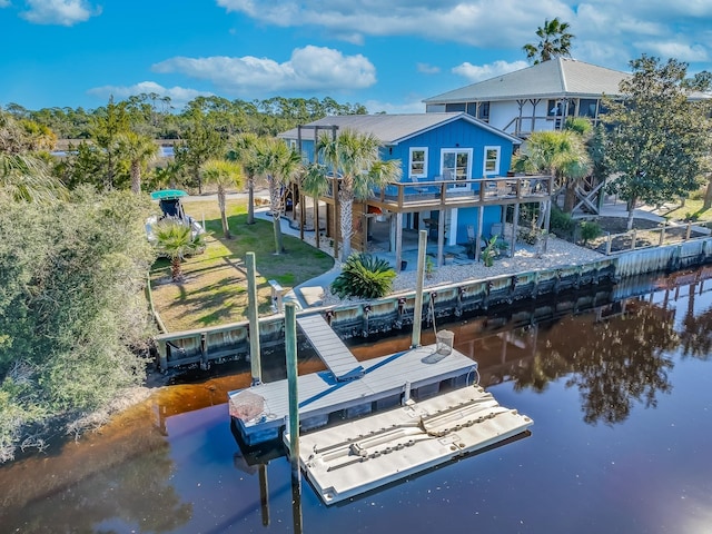 back of house featuring a patio area, a lawn, and a deck with water view