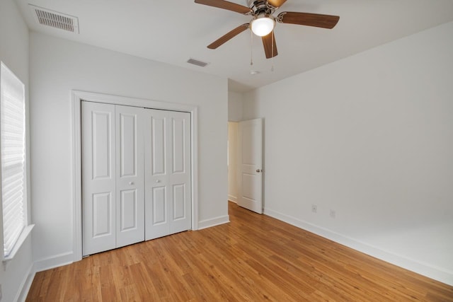 unfurnished bedroom featuring ceiling fan, light hardwood / wood-style floors, a closet, and multiple windows