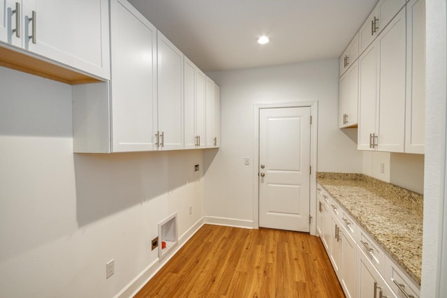 clothes washing area with cabinets, washer hookup, and light wood-type flooring