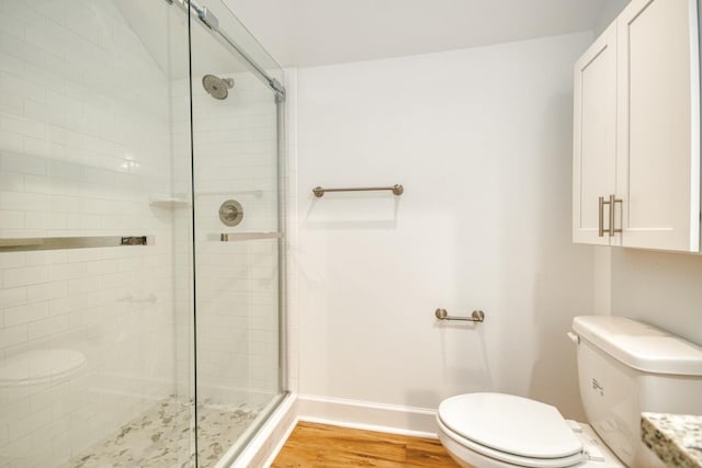 bathroom featuring hardwood / wood-style floors, a shower with door, and toilet