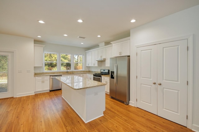 kitchen featuring light wood-type flooring, stainless steel appliances, a kitchen island, and white cabinetry