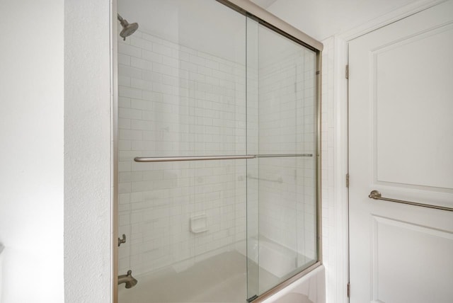 bathroom with bath / shower combo with glass door