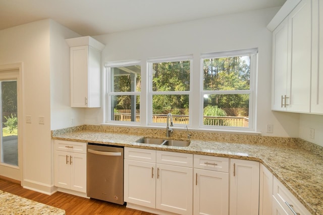 kitchen with dishwasher, sink, light stone countertops, light wood-type flooring, and white cabinetry