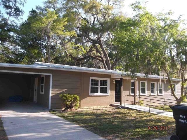 312 W Margurite St, Perry, FL 32347 - ranch-style house with concrete driveway, a carport, a metal roof, and concrete block siding