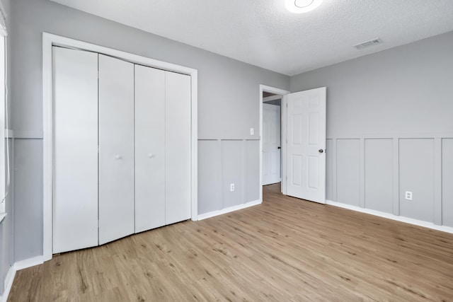11124 Bexhill Ln, Tallahassee, FL 32317 - unfurnished bedroom featuring a decorative wall, a textured ceiling, visible vents, a wainscoted wall, and wood finished floors