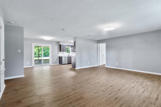11124 Bexhill Ln, Tallahassee, FL 32317 - unfurnished living room with a textured ceiling, visible vents, dark wood-style flooring, a sink, and baseboards