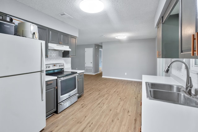 11124 Bexhill Ln, Tallahassee, FL 32317 - kitchen with visible vents, a sink, freestanding refrigerator, under cabinet range hood, and stainless steel range with electric cooktop