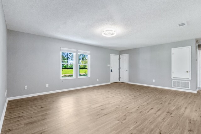11124 Bexhill Ln, Tallahassee, FL 32317 - unfurnished living room featuring a textured ceiling, wood finished floors, baseboards, and visible vents