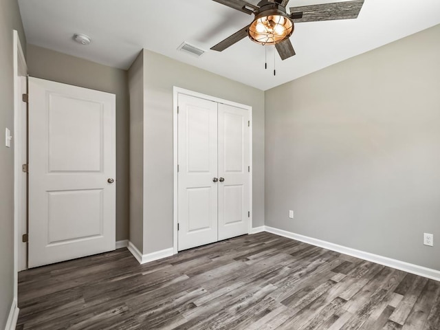 unfurnished bedroom with dark wood-type flooring, a closet, and ceiling fan