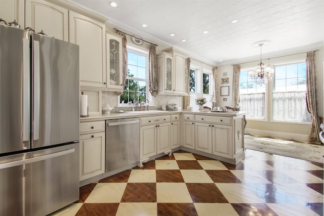 2460 Canopy Ln, Perry, FL 32347 - kitchen with stainless steel appliances, cream cabinetry, a sink, ornamental molding, and healthy amount of natural light
