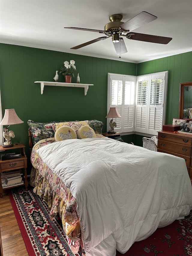 bedroom with hardwood / wood-style flooring, ceiling fan, and wooden walls