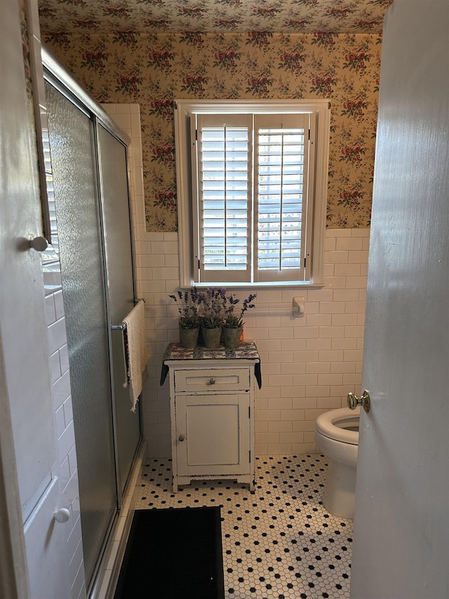 bathroom with tile patterned floors, toilet, tile walls, and an enclosed shower