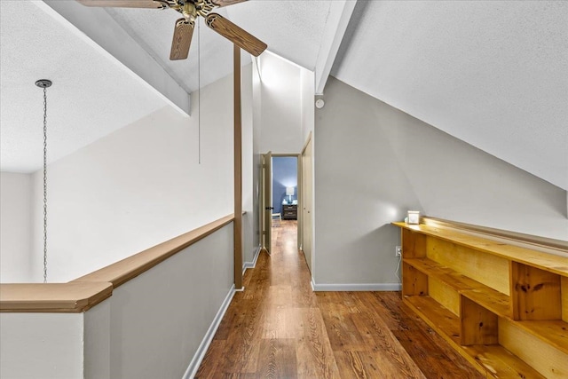 hall featuring hardwood / wood-style floors, lofted ceiling with beams, and a textured ceiling