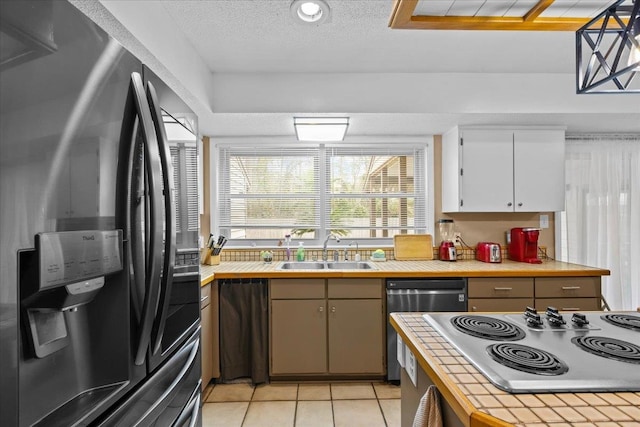 kitchen featuring sink, light tile patterned floors, appliances with stainless steel finishes, decorative light fixtures, and white cabinetry