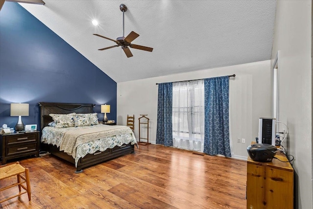 bedroom featuring a textured ceiling, light hardwood / wood-style floors, high vaulted ceiling, and ceiling fan