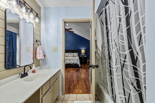 bathroom with vanity, a textured ceiling, shower / tub combo with curtain, vaulted ceiling, and wood-type flooring