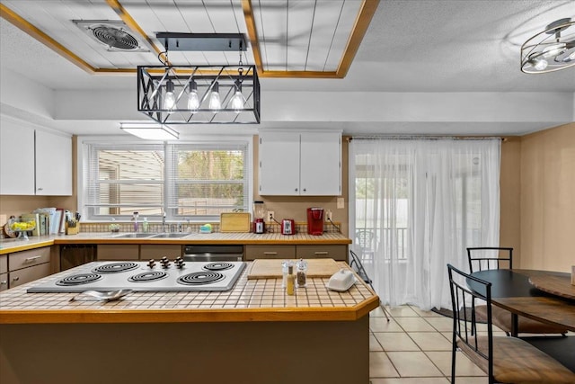 kitchen featuring a wealth of natural light, white cabinets, and hanging light fixtures