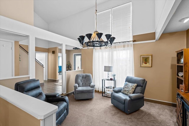 living area with carpet flooring, a chandelier, and high vaulted ceiling