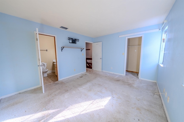 unfurnished bedroom featuring ensuite bath, a closet, and light carpet