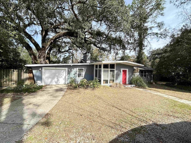 ranch-style house featuring fence, an attached garage, driveway, and a chimney