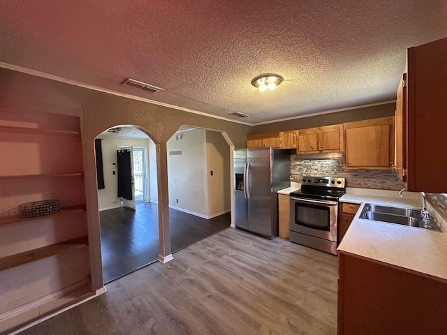 kitchen featuring stainless steel appliances, ornamental molding, sink, and light wood-type flooring
