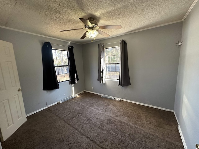 empty room with crown molding, a healthy amount of sunlight, ceiling fan, and dark carpet