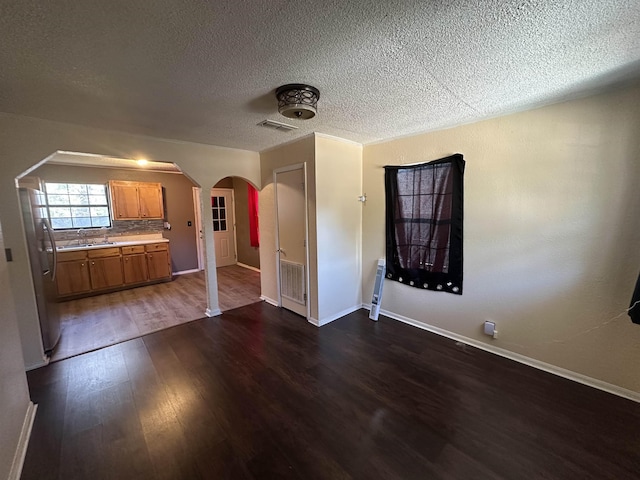 unfurnished living room with dark hardwood / wood-style floors, sink, and a textured ceiling