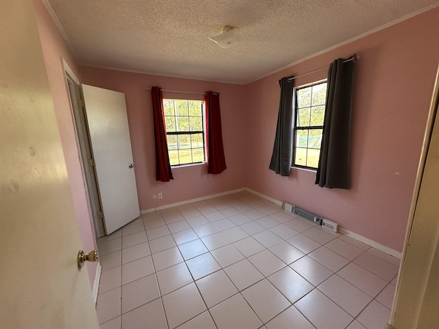 tiled empty room featuring plenty of natural light, ornamental molding, and a textured ceiling