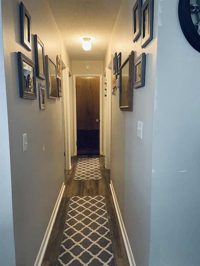 hallway featuring a textured ceiling and dark hardwood / wood-style floors