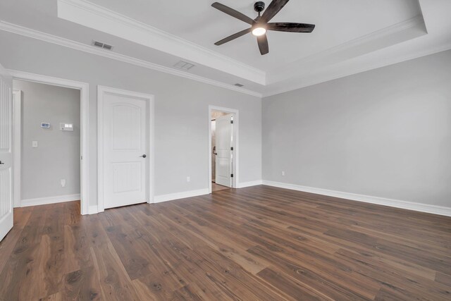 unfurnished bedroom with ensuite bathroom, a raised ceiling, ceiling fan, dark hardwood / wood-style floors, and ornamental molding