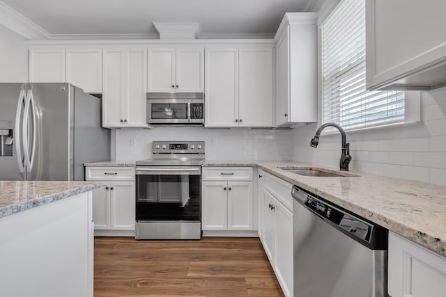 kitchen with light stone countertops, appliances with stainless steel finishes, white cabinetry, and sink