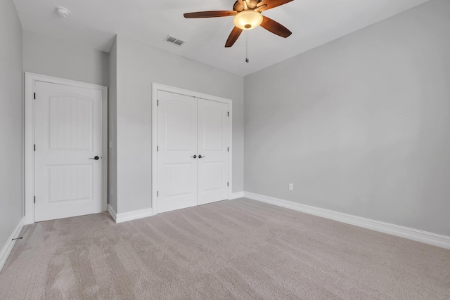 unfurnished bedroom with ceiling fan, light colored carpet, and a closet