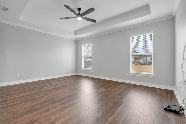 spare room with a raised ceiling, ceiling fan, dark wood-type flooring, and crown molding