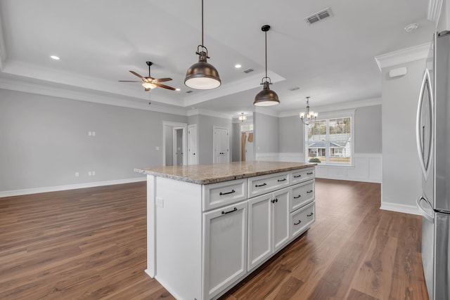 kitchen with pendant lighting, a center island, stainless steel fridge, light stone countertops, and white cabinetry