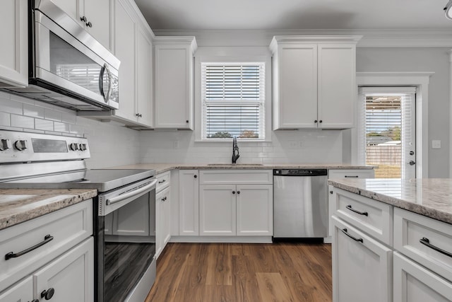 kitchen featuring light stone countertops, sink, backsplash, white cabinets, and appliances with stainless steel finishes