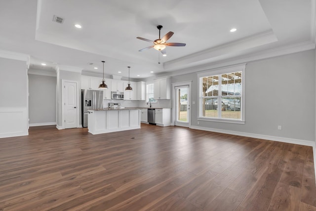 unfurnished living room featuring a raised ceiling, ceiling fan, and ornamental molding