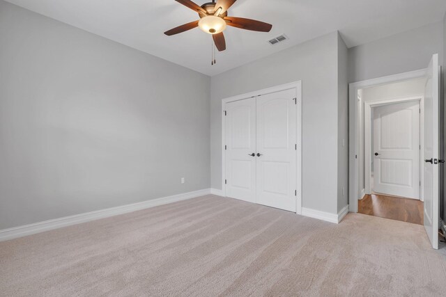 unfurnished bedroom with ceiling fan, light colored carpet, and a closet