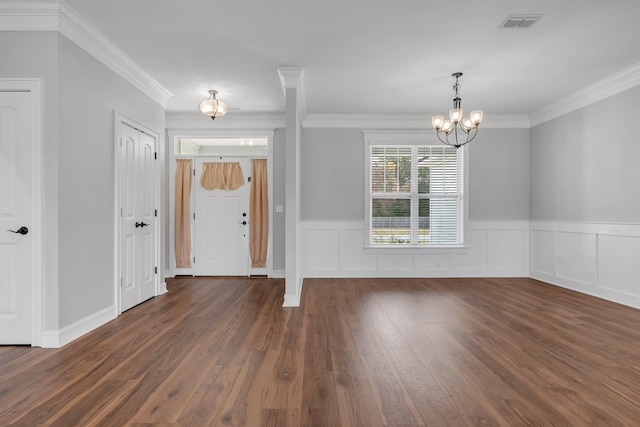 entryway with dark hardwood / wood-style flooring, ornamental molding, and a notable chandelier