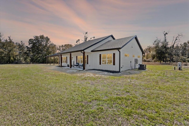 back of property at dusk with central air condition unit, a patio area, and a lawn