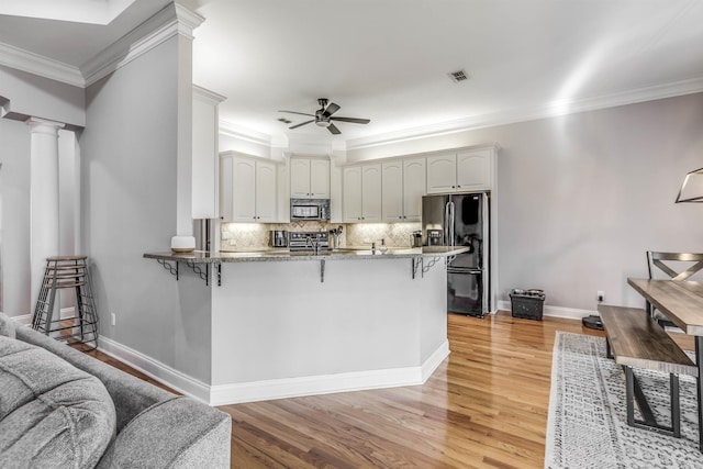 832 Eagle View Dr, Tallahassee, FL 32311 - kitchen featuring black appliances, a ceiling fan, a breakfast bar, a peninsula, and ornamental molding