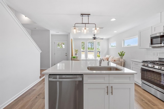 kitchen featuring decorative backsplash, appliances with stainless steel finishes, ceiling fan, sink, and white cabinets