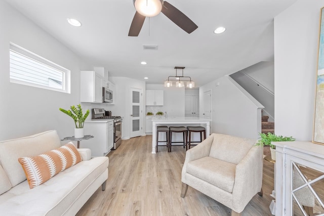 living room featuring ceiling fan, sink, and light wood-type flooring