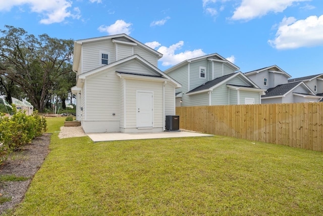 rear view of property featuring central AC unit, a patio area, and a lawn