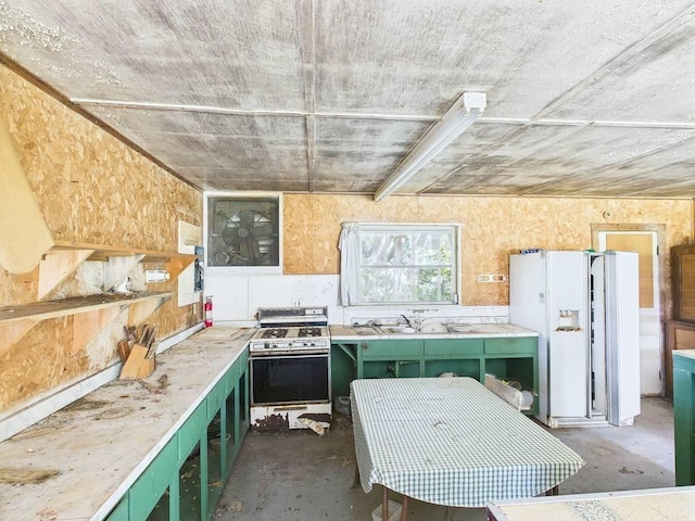 10815 Cooey Island Gr, Perry, FL 32347 - kitchen featuring gas range oven, green cabinetry, concrete floors, white fridge with ice dispenser, and light countertops