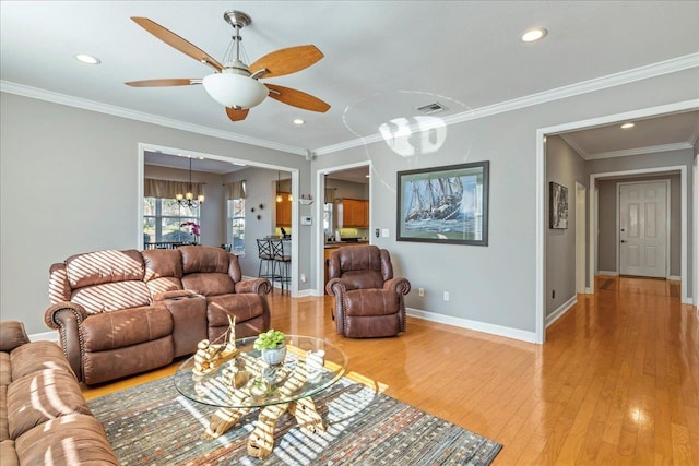 living room featuring hardwood / wood-style flooring, crown molding, and ceiling fan with notable chandelier