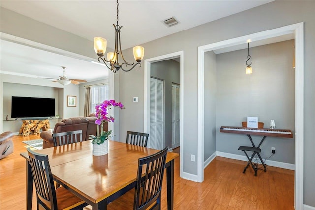 dining area with ceiling fan with notable chandelier and light wood-type flooring