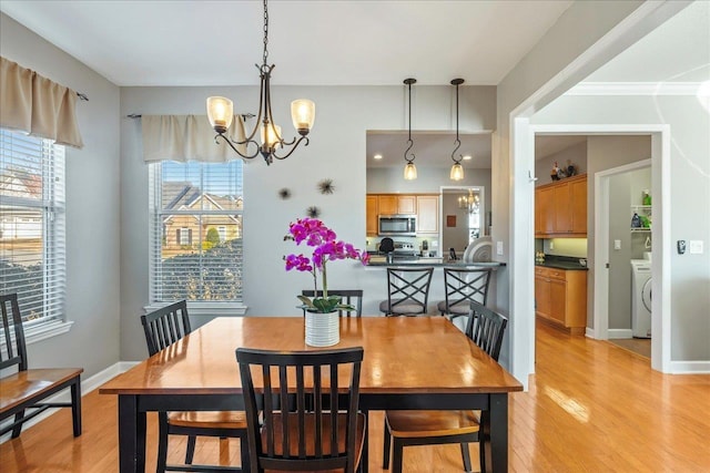 dining space featuring plenty of natural light, washer / dryer, a notable chandelier, and light wood-type flooring