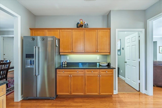 kitchen with dark stone counters, high end fridge, and light hardwood / wood-style flooring